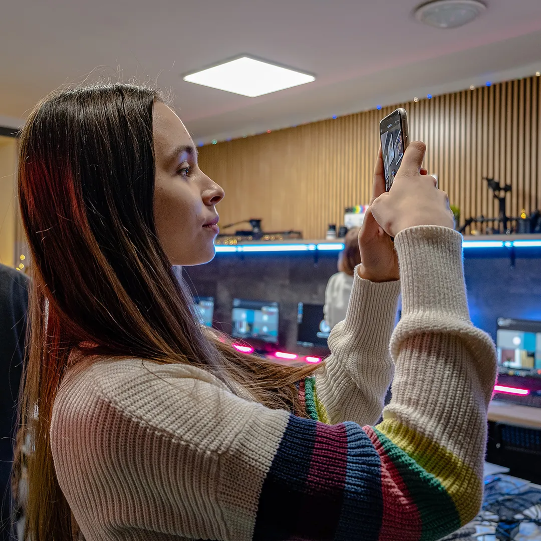 Uczennica fotografuje smartfonem, ćwicząc kadr i kompozycję podczas zajęć