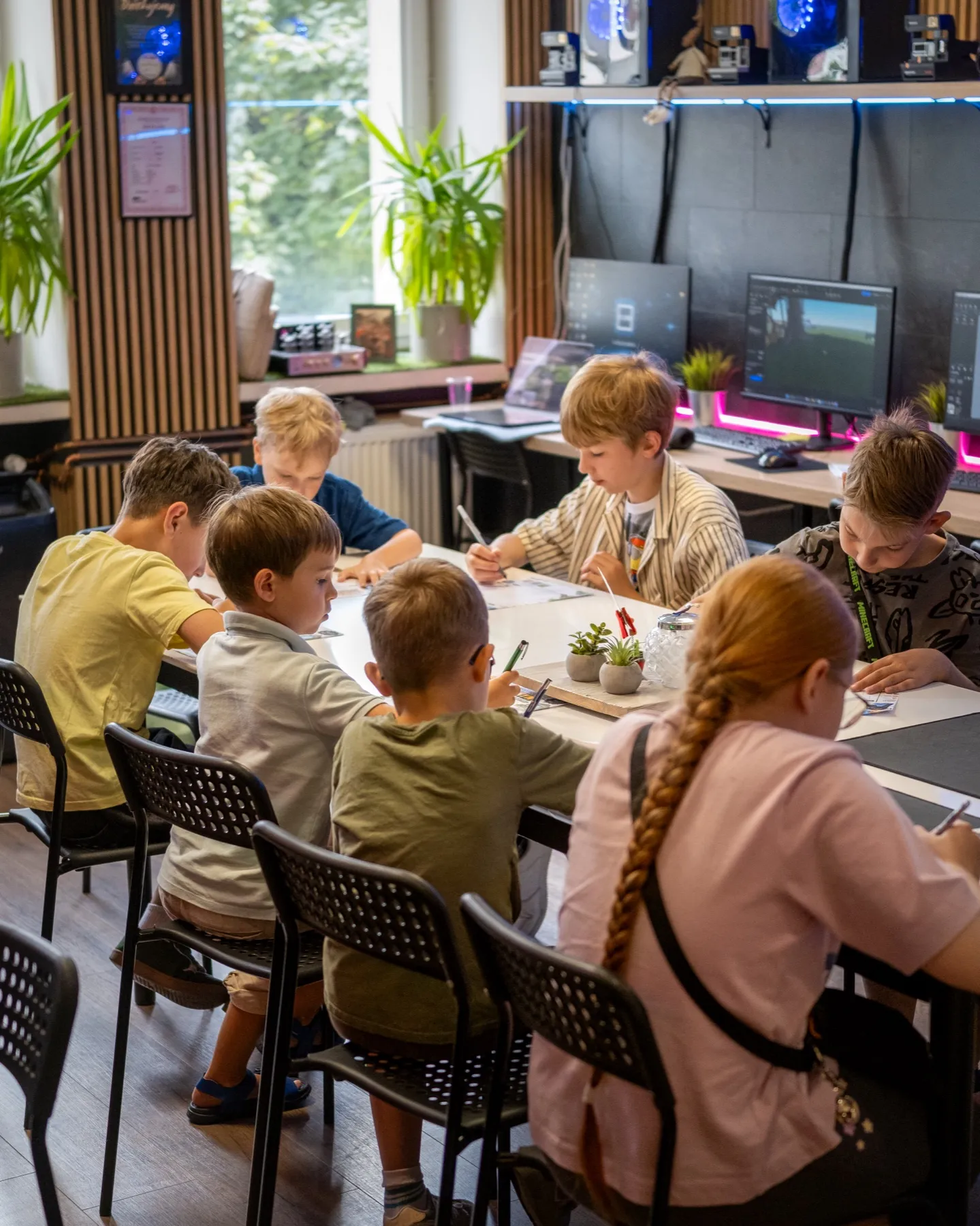 Dzieci wspólnie pracują przy stole podczas zajęć w IT-Club.Academy